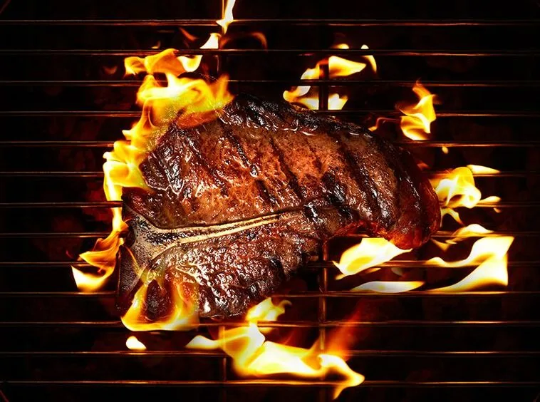 Steak searing over open flame on the charcoal grill